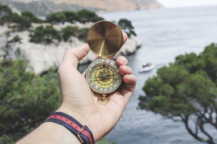 holding a compass in front of the sea
