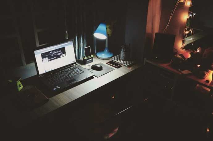 lone lamp on next to an open laptop late at night